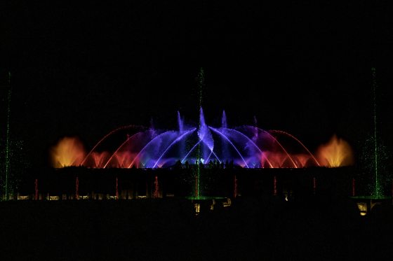 A nighttime fountain show with the water lit up in a spectrum of colors. 